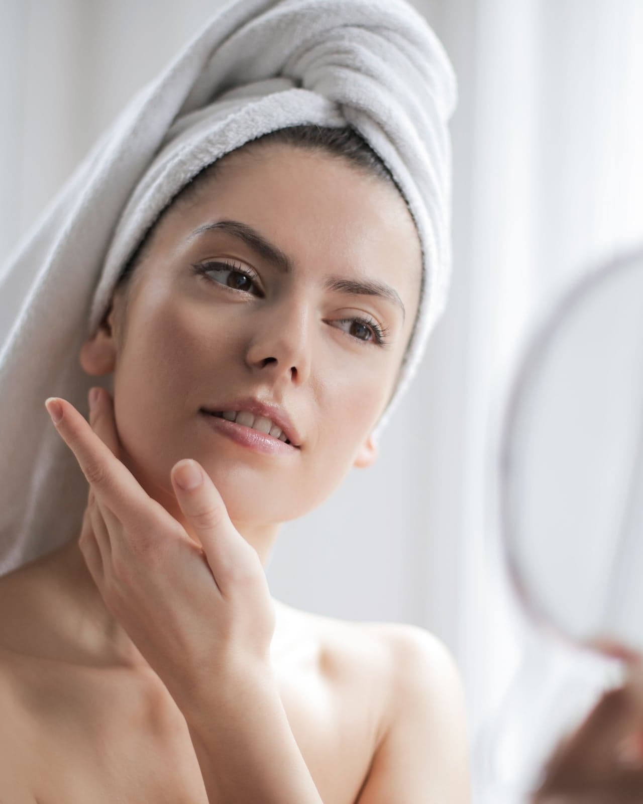 Stock photo of a woman looking at her reflection in a handheld mirror
