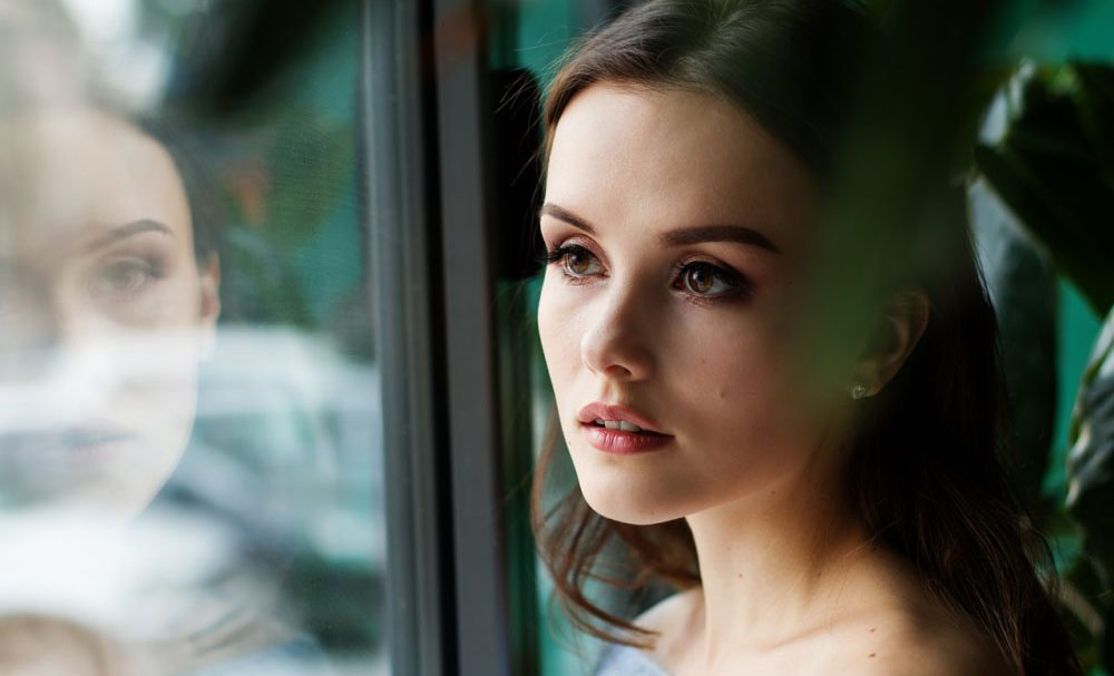 Woman looking at her reflection in a window